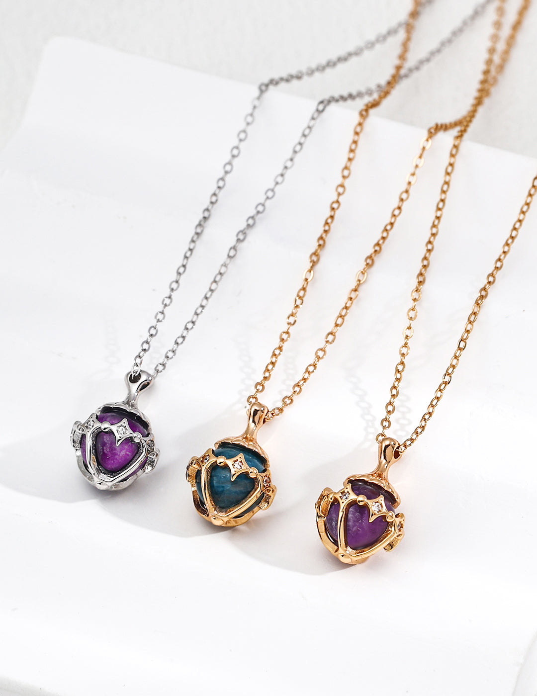 Three necklaces with heart-shaped pendants in different colors on a white background